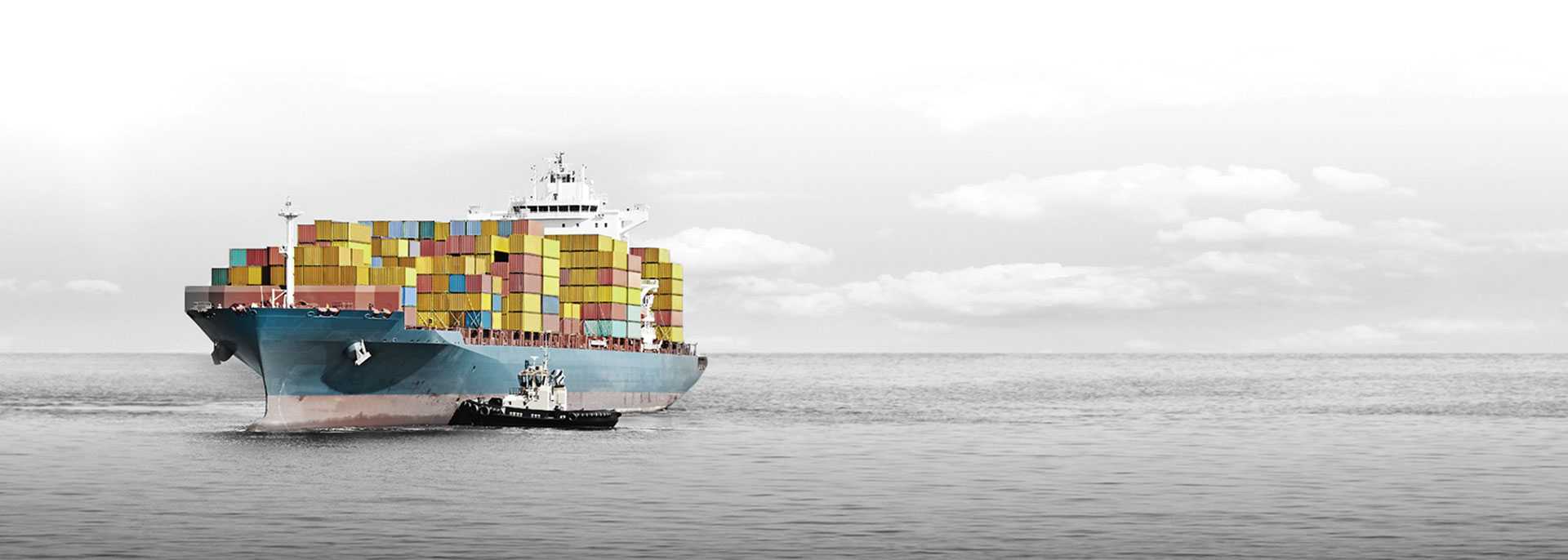 Large shipping boat on the open ocean, the boat and shipping containers are in color and the rest in black and white